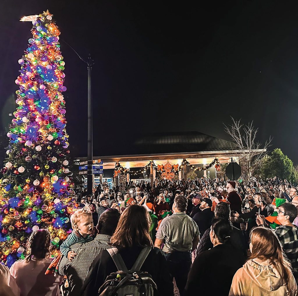 Crowd celebrating Christmas in the Pass beside a decorated tree